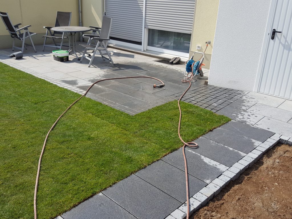 Terrassenbau mit großformatigen Betonplatten und Rasenkante – Außenanlagen in Köln
